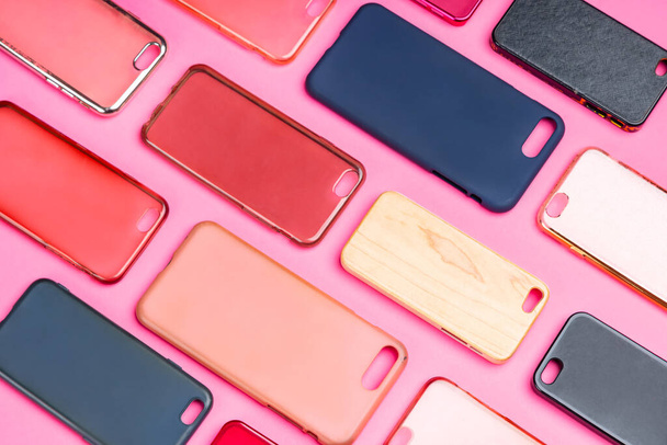 Stapel von bunten Plastikrückdeckeln für Mobiltelefone. Auswahl an Smartphone-Schutzzubehör auf rosa Hintergrund. Viele Silikonrückseiten oder -häute nebeneinander - Foto, Bild
