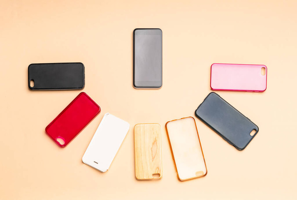 Elección de cubiertas traseras de plástico multicolor para teléfonos móviles en un fondo neutro con un teléfono inteligente en el lateral - Foto, imagen
