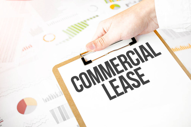 Text commercial lease on white paper plate in businessman hands with financial diagram. Business concept - Photo, image
