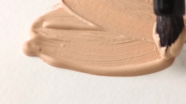 beige smear of tonal foundation cream close up, smudge with a brush, beautiful pastel texture, cosmetic product for make up - Video