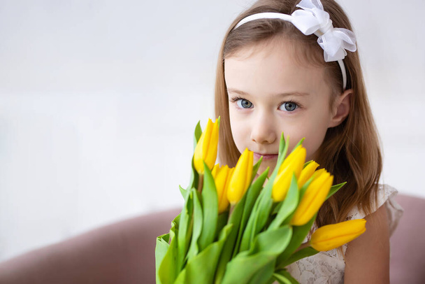 Cute little girl with a bouquet of tulips. The concept of happy people, spring mood. - 写真・画像