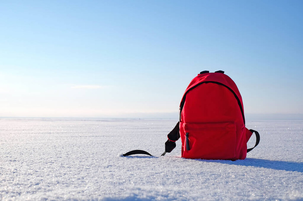 Red packbag on snow and blue winter sky. Copy space - Photo, image