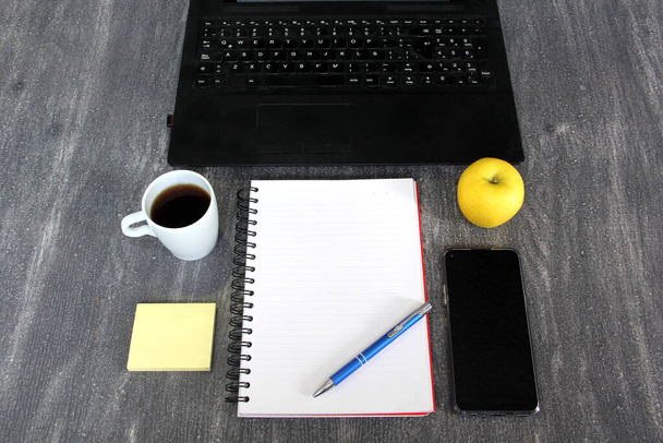 oficina en casa laptop, celular, libreta de apuntes boligrafo, cafe manzana - Photo, Image
