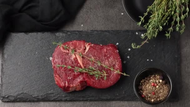 свіжий сирий стейк з м'ясом на чорній кам'яній тарілці збільшує. м'ясо і спеції на кухонному столі вид зверху
 - Кадри, відео