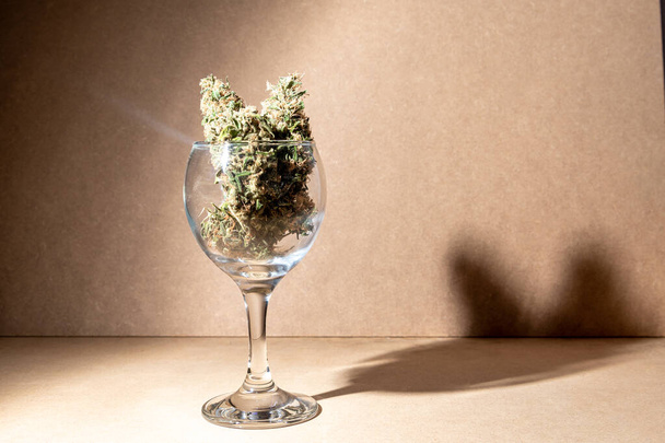 Pronto a consumare germogli di marijuana medica all'interno di un vetro di cristallo.Focus selettivo su sfondo marrone. - Foto, immagini