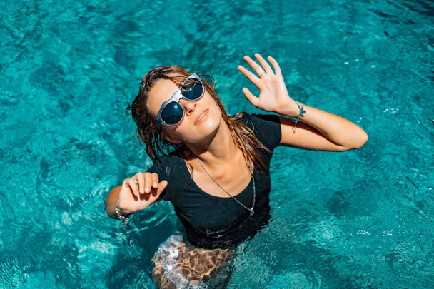 young tanned woman in sunglasses in the pool, fashion, splashes. - Foto, Bild