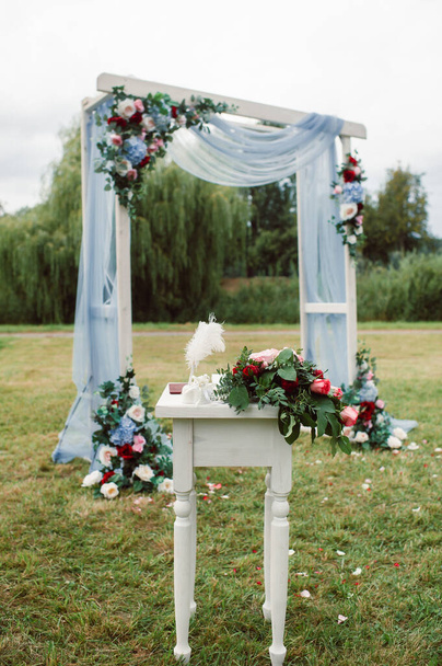Wedding ceremony on the street on the green lawn.Decor with fresh flowers arches for the ceremony. - Foto, Imagen