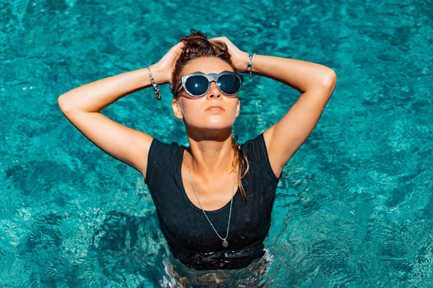 young tanned woman in sunglasses in the pool, fashion, splashes. - Foto, Imagem