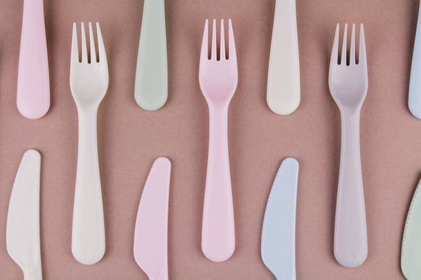 a set of plastic cutlery in different colors spoons forks knives on the kitchen table and eco-friendly plastic - Foto, Imagen