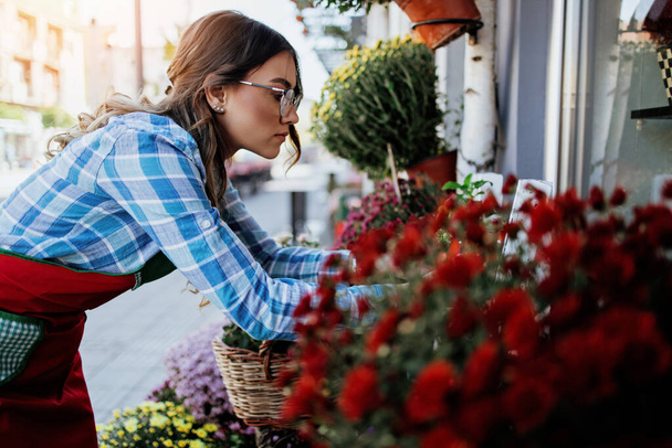 Young adult woman working in city street flower shop or florist. Small business concept. - 写真・画像