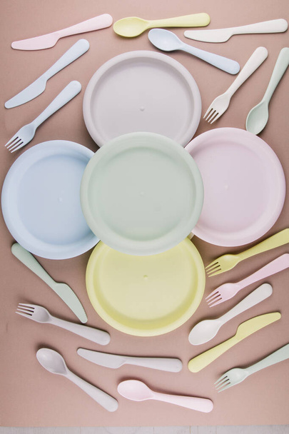 set of plastic colored dishes with a plate fork spoon knife on the table eco-friendly tableware - Фото, зображення