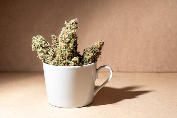Des bourgeons de marihuana médicale dans une tasse de café. Focus sélectif sur fond brun. - Photo, image