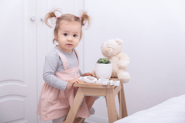 funny toddler girl playing with toys at home in white room. - Фото, изображение