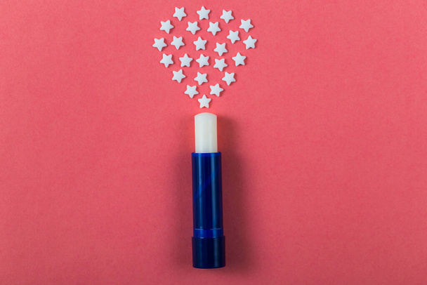 Witte hygiënische lippenstift voor lippen met sterren ligt op een roze papieren achtergrond. Bovenaanzicht. - Foto, afbeelding
