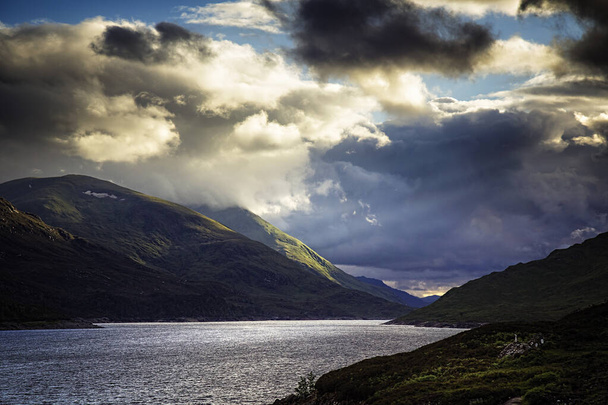 Dramatisch zonlicht en wolken bij Loch Mullardoch, een stuwmeer in de Schotse hooglanden. - Foto, afbeelding