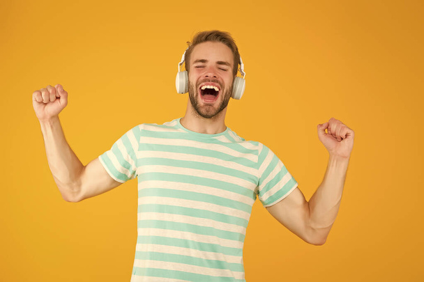 Music makes me happy. Happy man listen to music yellow background. Handsome guy enjoy melody playing in headphones. Happy music. Pleasure and joy. Fun and entertainment. Happy new mix. Super hit - Fotoğraf, Görsel