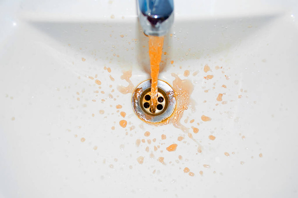 Rust flowing from the tap in the bathroom. Concept of the problem is dirty water - Zdjęcie, obraz