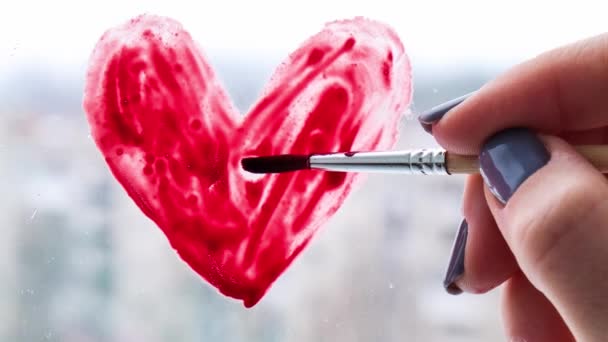 Mano de una chica con un pincel pintando el corazón rojo en una ventana, quedarse en casa, ocio cuarentena, vamos a estar bien, Día de San Valentín, Amor 4k Zoom in - Metraje, vídeo