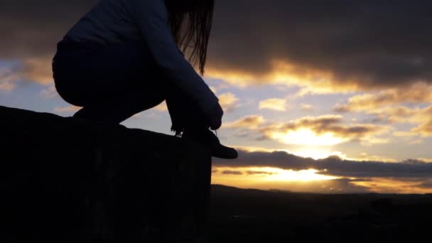 A nő nyugszik sziklás táj ellen naplemente és a felhők - Felvétel, videó