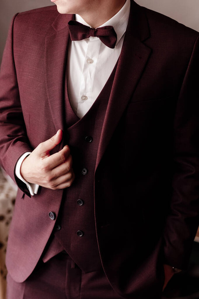 Mężczyzna w eleganckim brązowym smokingu z jedwabną muszką i zegarkiem. ukierunkowanie selektywne - Zdjęcie, obraz