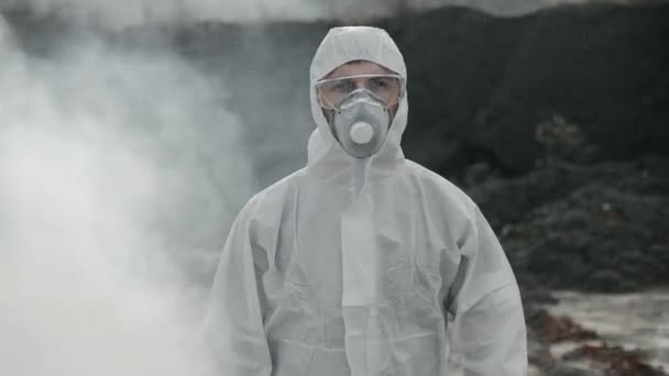 Portret van een laboratoriumassistent in een masker die uit giftige rook komt met een gereedschapskist - Video