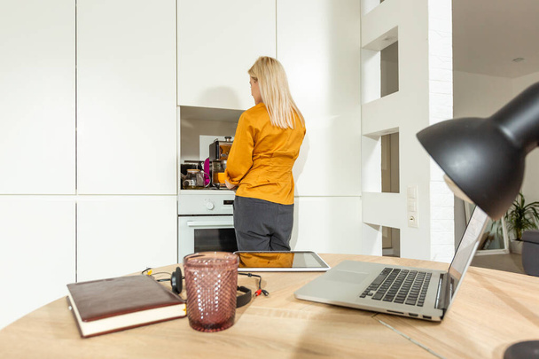 Πορτρέτο της γυναίκας που εργάζονται με φορητό υπολογιστή σε φωτεινή κουζίνα. Ιός Covid-19. Κοινωνική απόσταση - Φωτογραφία, εικόνα