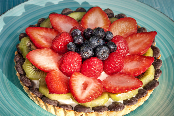 Tarta grande de frutas con bayas mixtas, incluyendo fresas rojas, bayas azules, frambuesas rojas y kiwi. - Foto, imagen