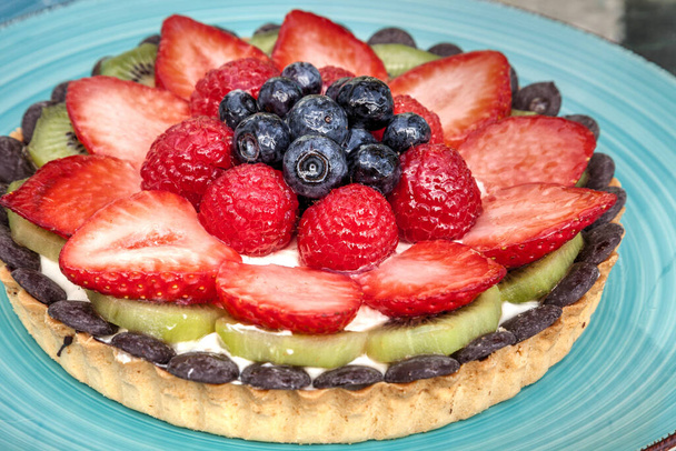 Grande tarte aux fruits aux baies mélangées, y compris les fraises rouges, les baies bleues, les framboises rouges et le kiwi. - Photo, image