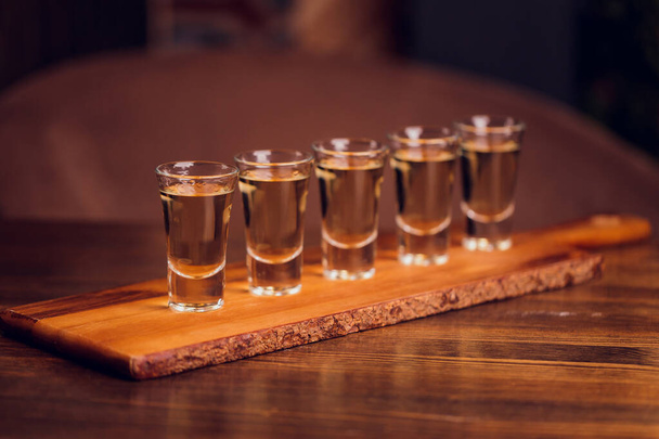 Variation of hard alcoholic shots served on bar counter. Blur bottles on background. - Foto, afbeelding