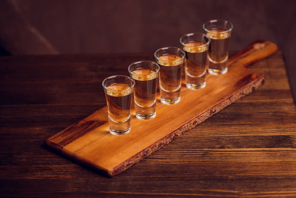 Variation of hard alcoholic shots served on bar counter. Blur bottles on background. - Foto, Imagem