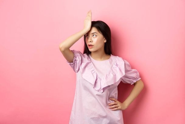 Ärtynyt aasialainen tyttö roll silmät ja facepalm, tunne väsynyt ja ärtynyt tyhmä keskustelu, seisoo vaaleanpunainen tausta - Valokuva, kuva