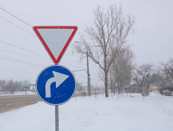 Дорога и дорожный знак в снежный день - замедление движения. - Фото, изображение
