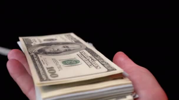 Mains masculines Scatter pile de 100 projets de loi en dollars américains sur fond noir. De l'argent. 4K - Séquence, vidéo
