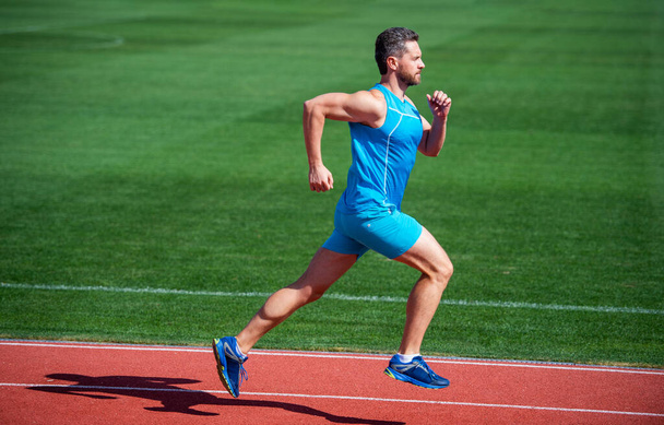 Athletic mature man running on stadium, speed - Foto, imagen