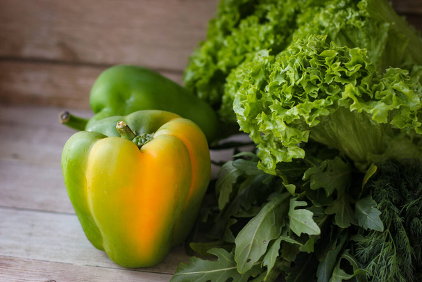 Das Konzept der gesunden Ernährung. Grüne Dillblätter und Rucola und Salat zusammen mit grünem Paprika auf Holzgrund - Foto, Bild