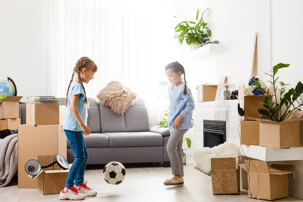 Kleine meisjes in de buurt van kartonnen doos, verhuizen naar een nieuw appartement - Foto, afbeelding