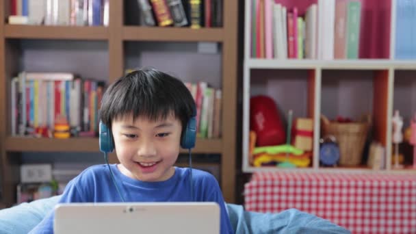 Szczęśliwy młody azjatycki chłopiec podczas połączenia wideo w domu mówi patrząc i uśmiechając się do kamery rozmowy zrobić wideo, edukacja koncepcja - Materiał filmowy, wideo