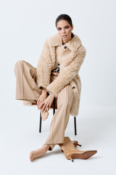 donna seduta su una sedia alla moda autunno abbigliamento di lusso - Foto, immagini