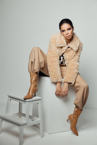 жінка на модному осінньому одязі позує сидячи коричневе взуття
 - Фото, зображення