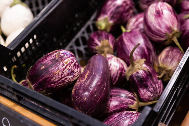 Plastic box with fresh eggplant on market counter - Foto, afbeelding