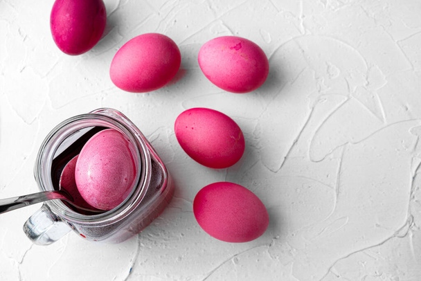 Painting Easter eggs in pink on white table, view from above - Foto, Bild