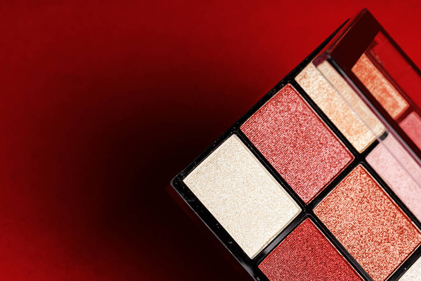 Makeup eyeshadow palette on the red background. - Foto, imagen
