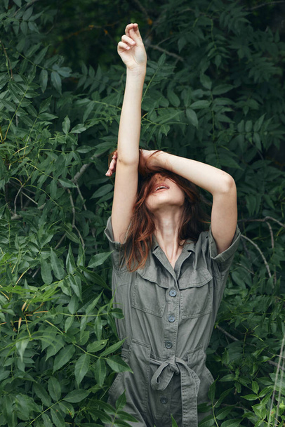 Woman outdoors holds his hands above his head green leaves - Foto, Imagem
