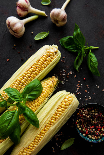 mazorca de maíz madura sobre fondo negro con especias - Foto, imagen
