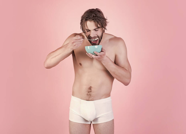 Man with wet hair eat breakfast on pink background. Sexy man with muscular body eating cereal, healthcare. Dieting and fitness, calorie. Food and beauty, health. Morning, vegetarian, organic food. - Φωτογραφία, εικόνα