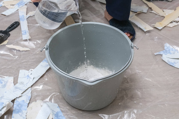 Mixing white plaster in a bucket with stirrer. Close-up. - Φωτογραφία, εικόνα