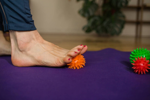 close-up of a person's foot doing massage with a ball with needles on the mat - Foto, afbeelding