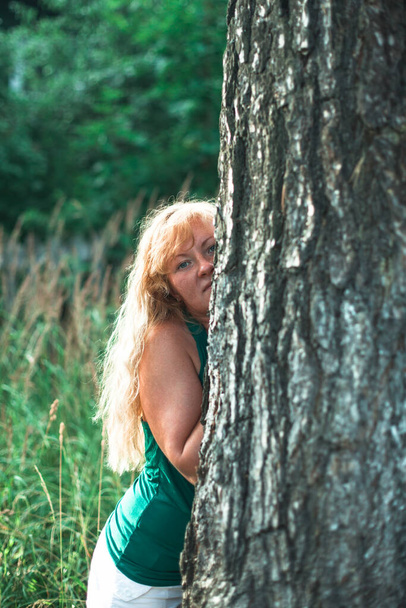 Portrait of a woman in the park near a pine tree. - Zdjęcie, obraz