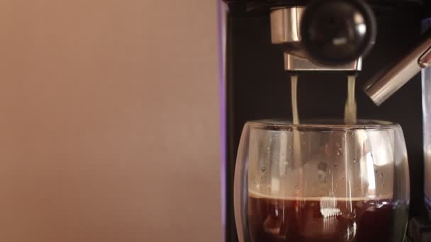 Espresso caliente que se ejecuta en la taza de vidrio doble. Cafetera vertiendo café expreso en un vaso. - Metraje, vídeo