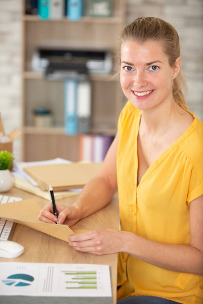 female office worker writing on an envelope - Zdjęcie, obraz